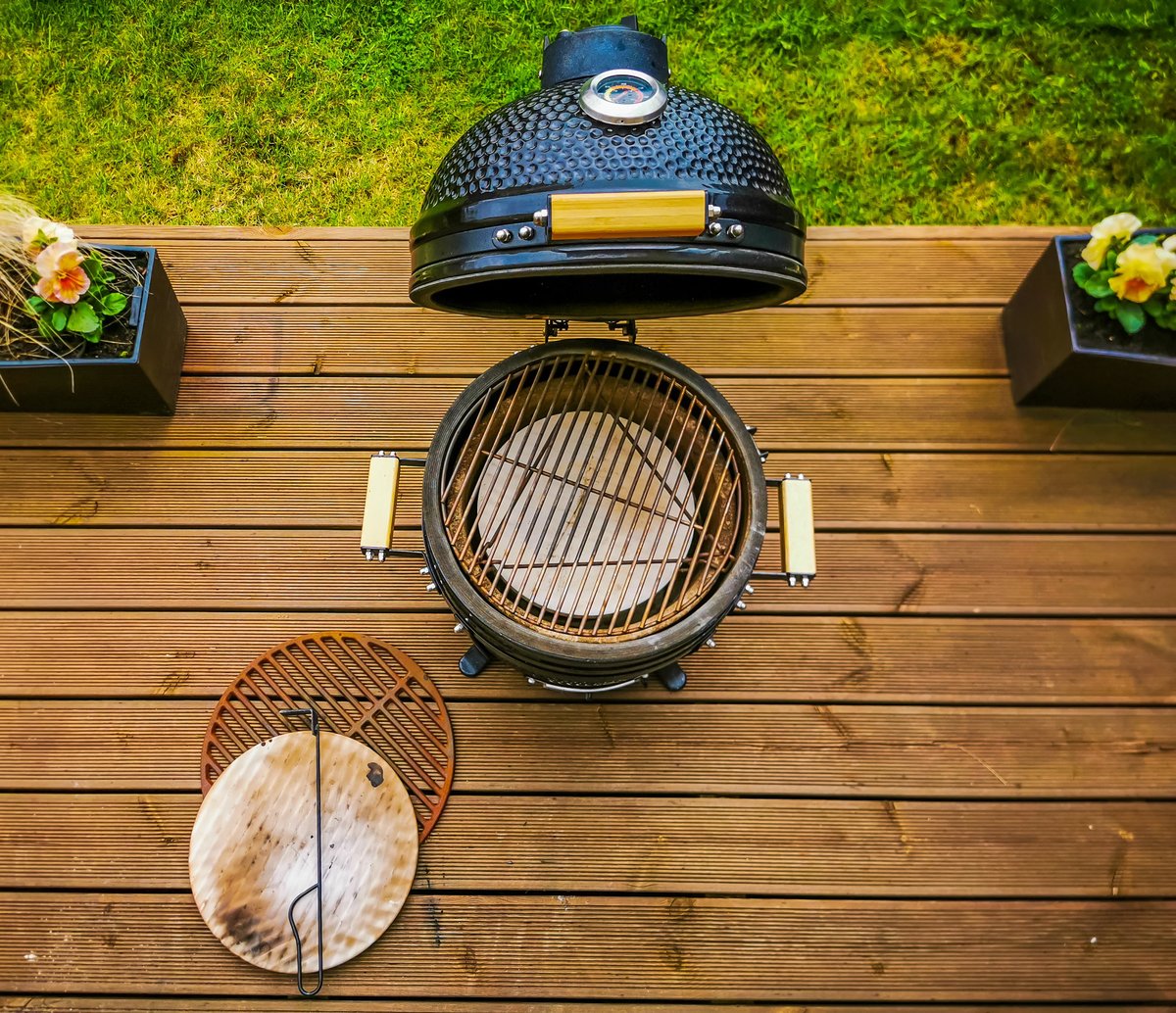 A kamado type barbeque grill with its accessories standing on a living house terrace