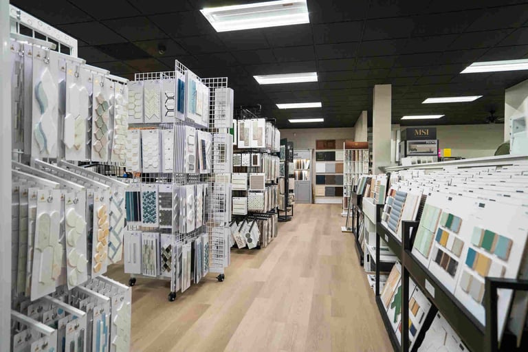 Interior of a tile and flooring showroom displaying various samples and patterns on walls and racks along an aisle.