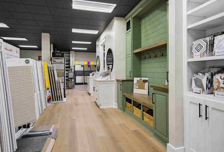 Interior of a home improvement showroom with wood flooring, display samples on walls, and green cabinetry with storage solutions.