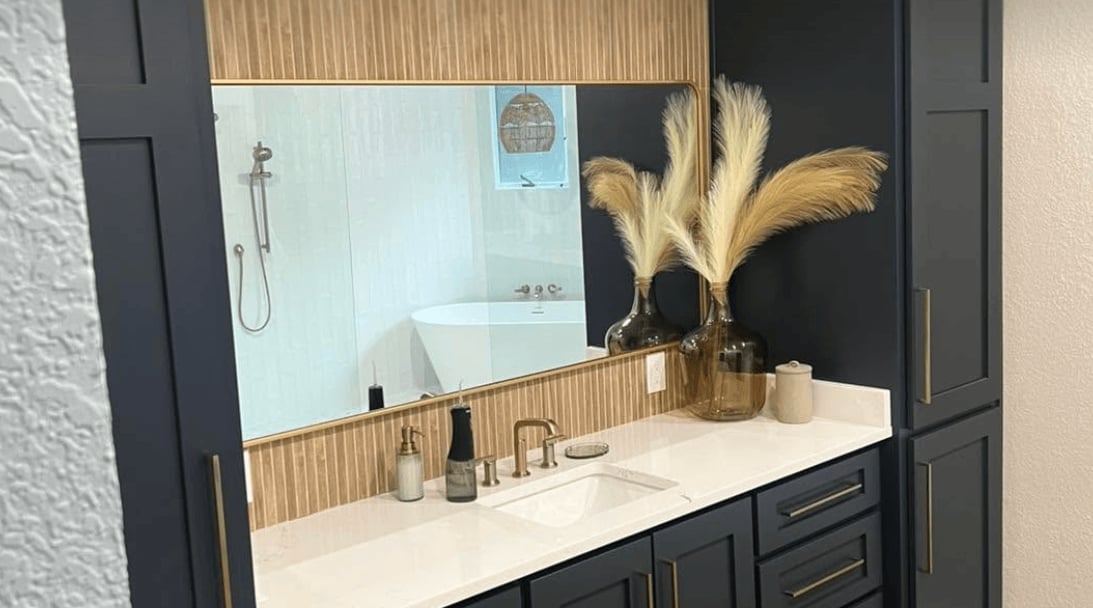 Modern bathroom vanity with black cabinetry, white countertop, large mirror, pampas grass decor, and chrome fixtures