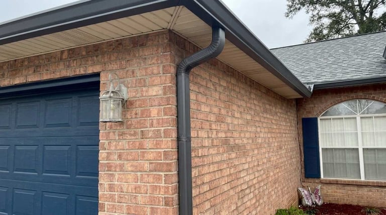 Brick residential house exterior with blue garage door and gutter system visible on the roofline