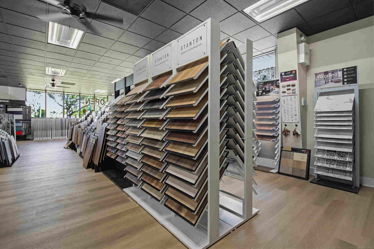 Interior of a flooring showroom displaying large sample displays of hardwood and laminate flooring options on rotating stands.