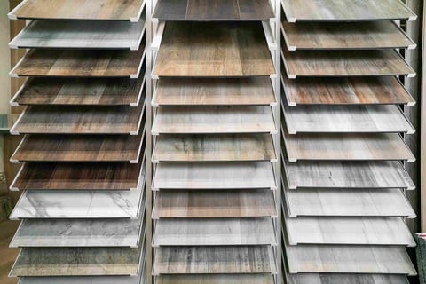 Three columns of wood flooring samples displayed on a wall showing various plank colors and finishes ranging from light to dark tones