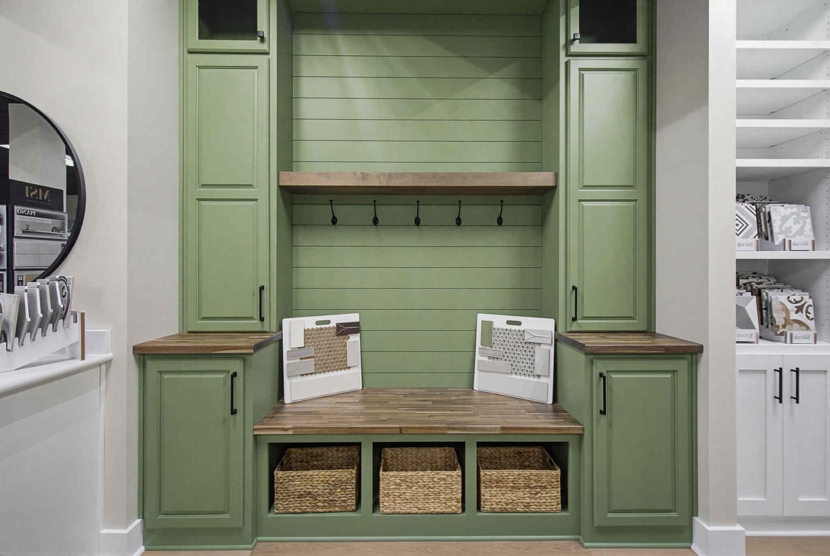 Green built-in mudroom with open shelving, hooks, and woven baskets for storage and organization