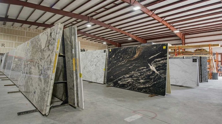 Marble and granite slabs displayed in warehouse showroom with metal beams overhead