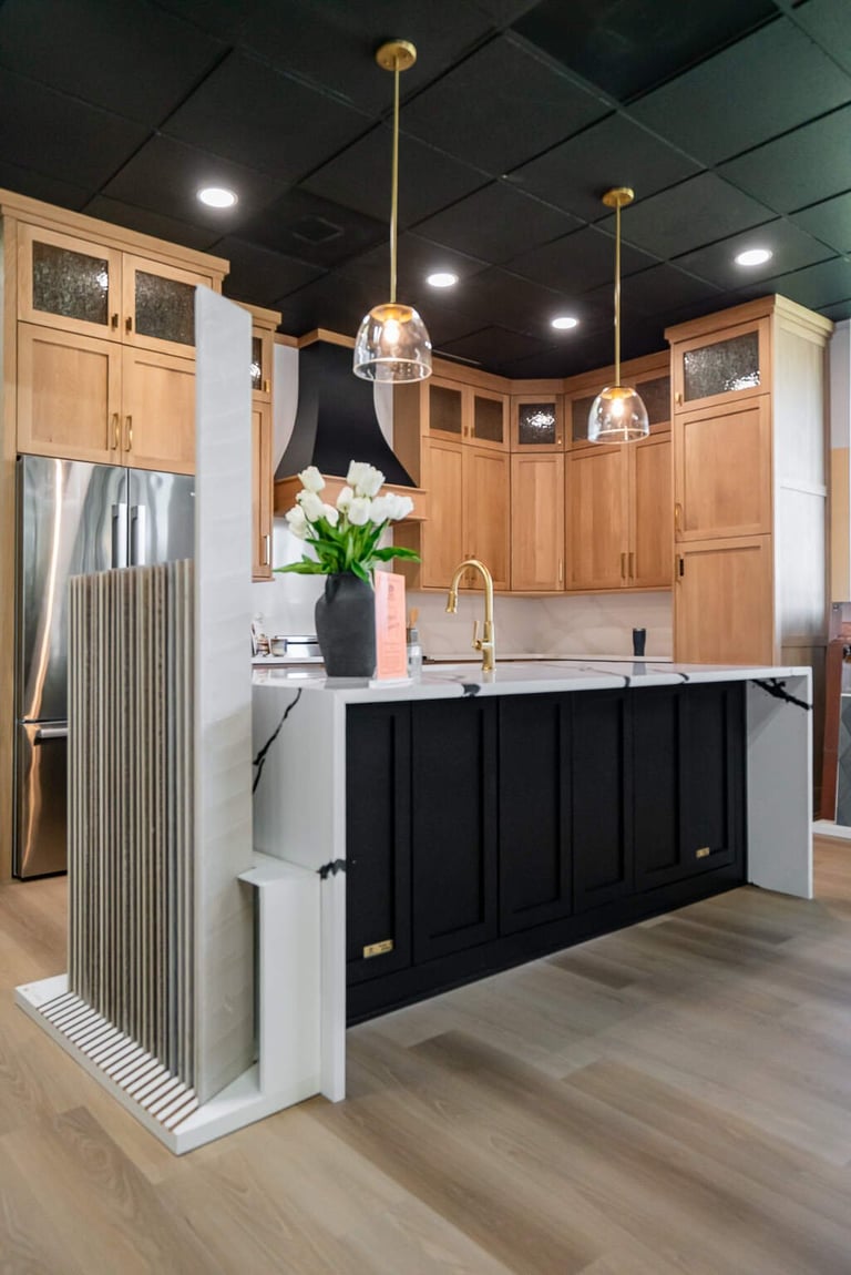 Modern kitchen showroom display with black island, wood cabinetry, brass pendant lights, and stainless steel appliances