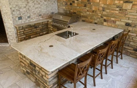 Indoor kitchen with stone countertop, bar seating, brick backsplash, and stove on the wall